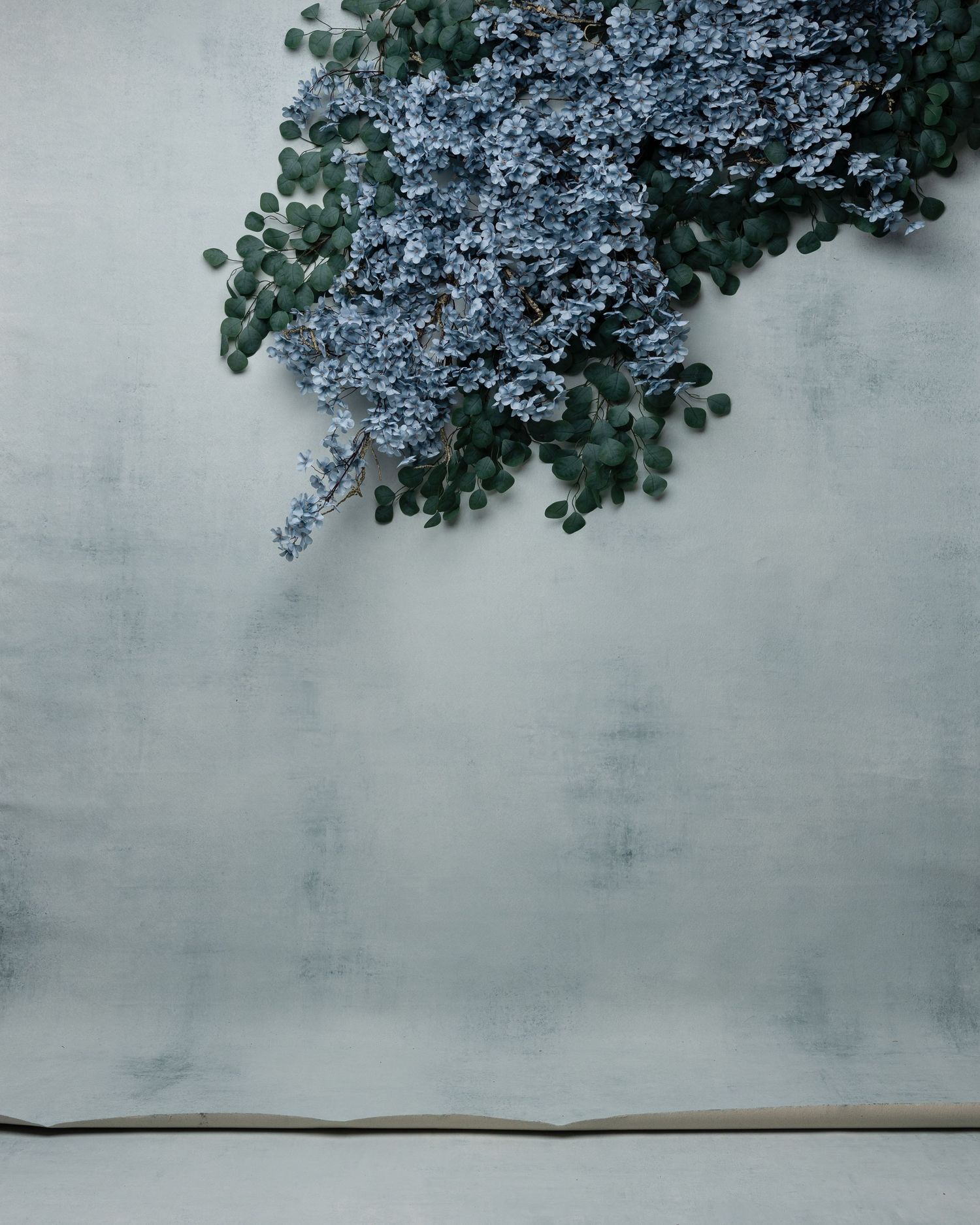 Red climbing roses cascade over a dark gray concrete wall and steps in a moody, minimalist setting.