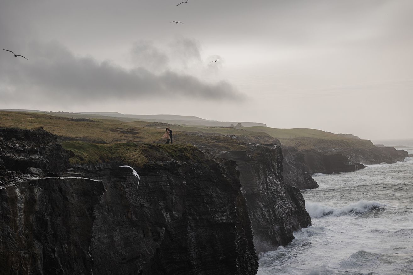 Couple silhouetted against sunset sky during Cliffs of Moher storytelling portrait session