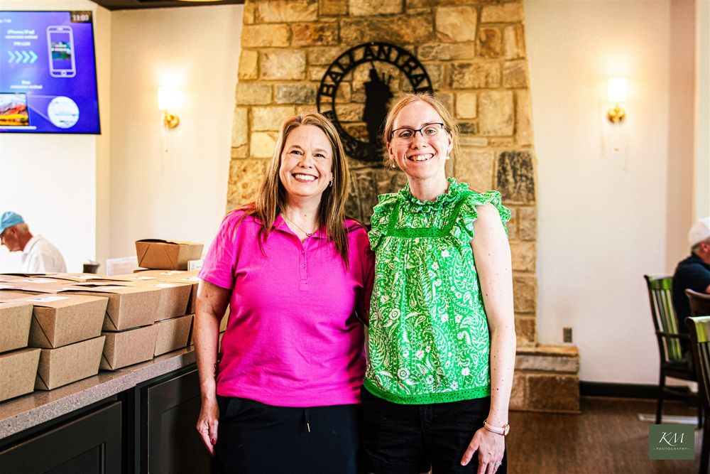 Two women smiling with catering at corporate event, Affordable Birmingham Alabama event photographer.