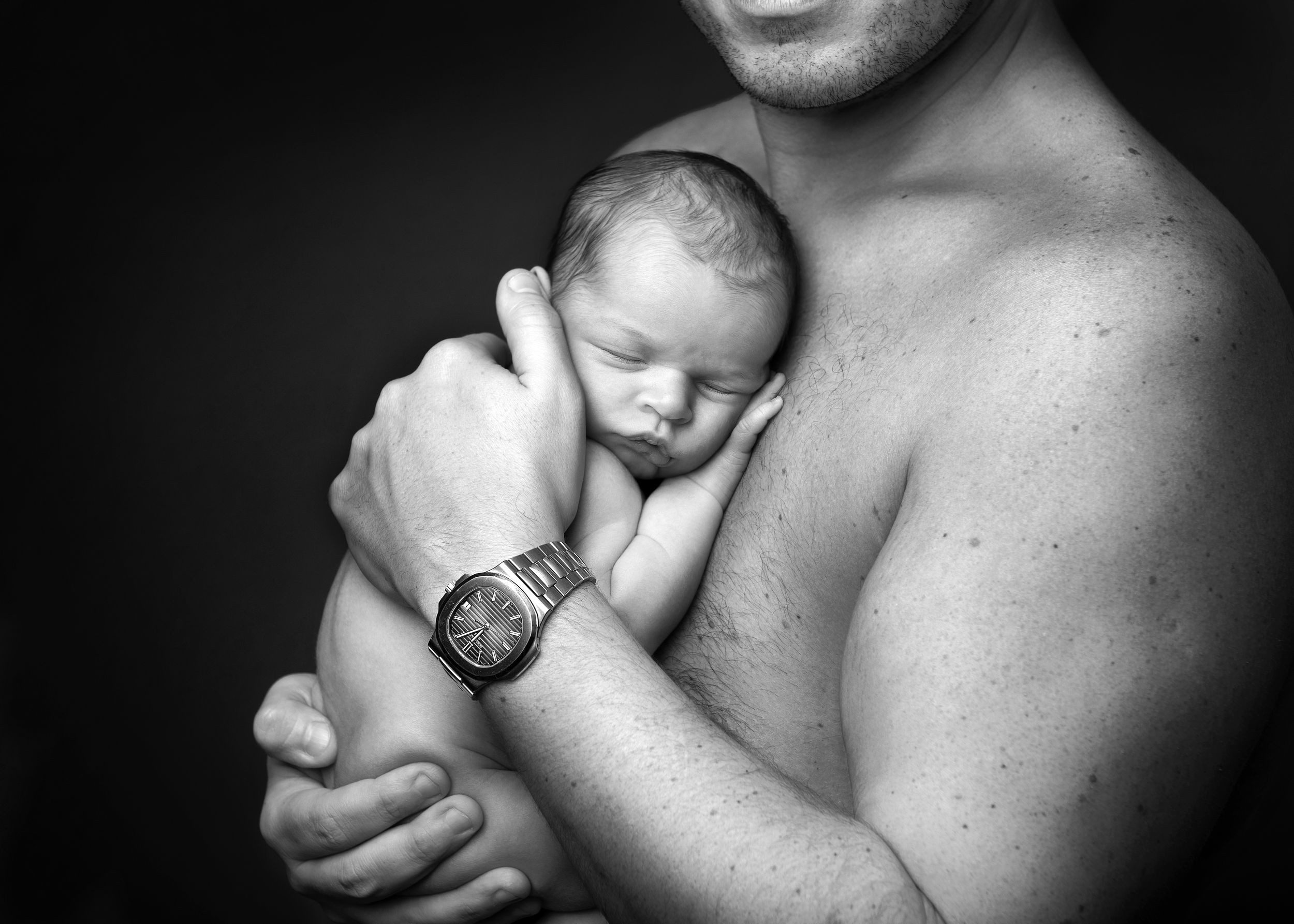 A tender black and white photo series showing intimate moments between a parent and newborn baby.