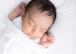 A sleeping newborn baby rests peacefully on white bedding in a series of connected photos.