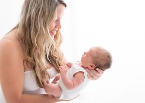 A tender moment between parent and newborn baby against a bright white background.