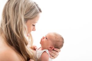 A parent and baby share a tender moment during a lifestyle photography session in natural light.
