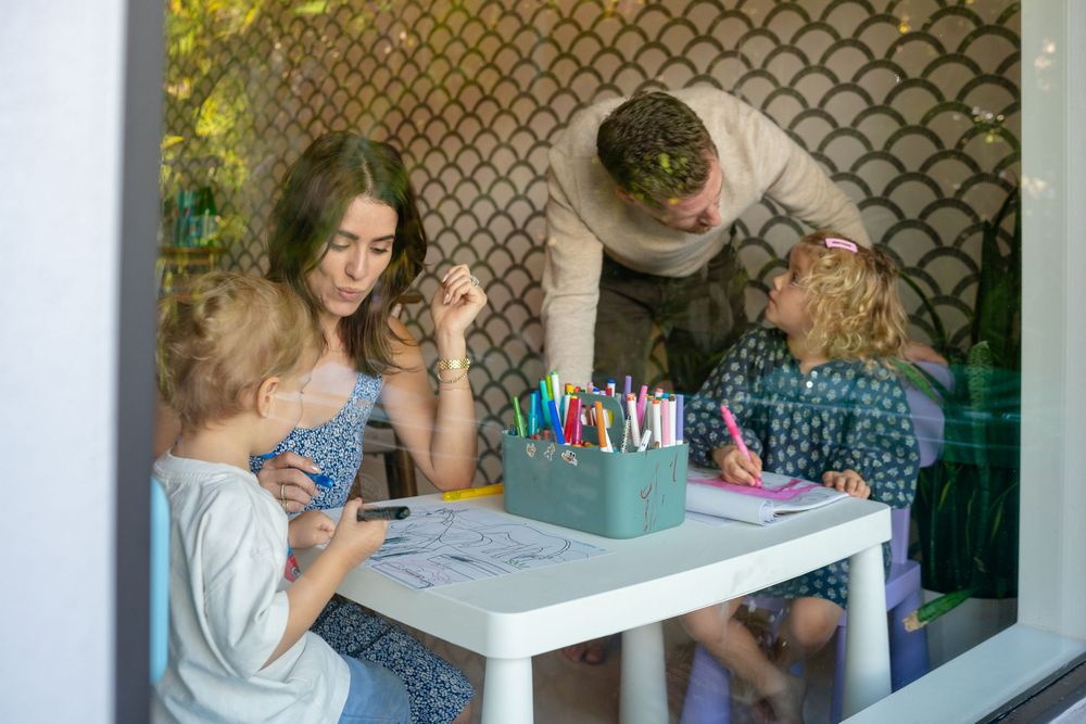 People gathered around a white table working on nail polish and manicures in a cozy indoor setting.