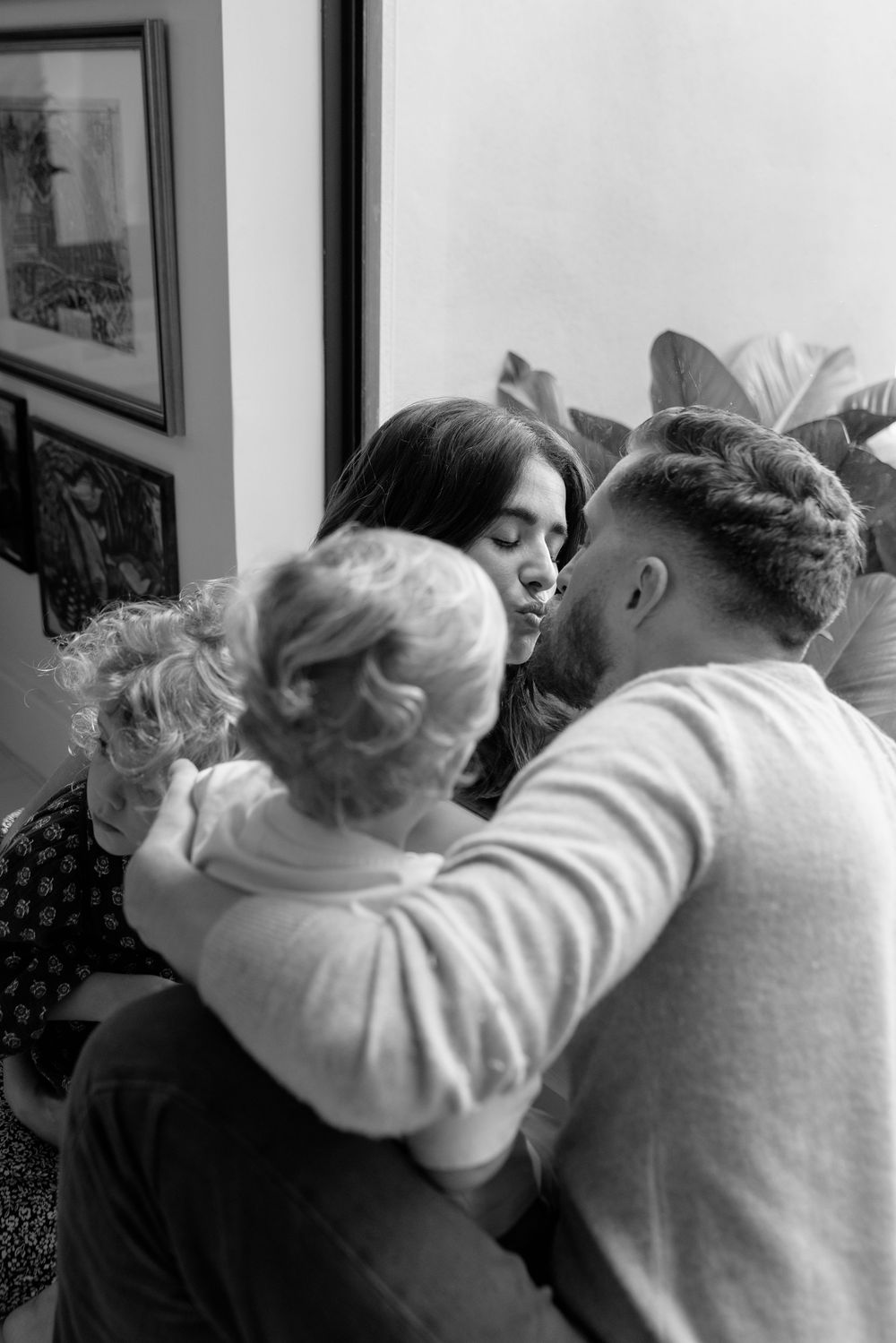 A tender black and white family moment showing parents embracing their young child in an intimate setting.