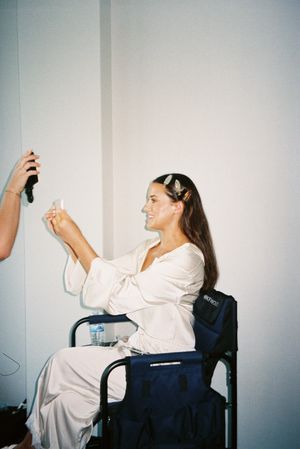 A sequence of four photos showing someone in a white shirt and dark pants sitting in a chair against a white wall.