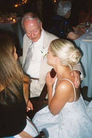 Wedding reception guests dancing and celebrating at an evening indoor venue with warm lighting.