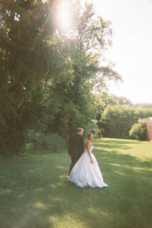 A white wedding dress flows across a sunlit green lawn as the wearer moves through a series of artistic photos.