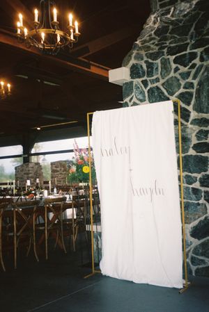 An elegant event space with stone walls, chandelier lighting, and cross-back chairs arranged around tables.