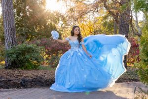 Flowing blue dress spreads elegantly across autumn forest path during outdoor photoshoot.