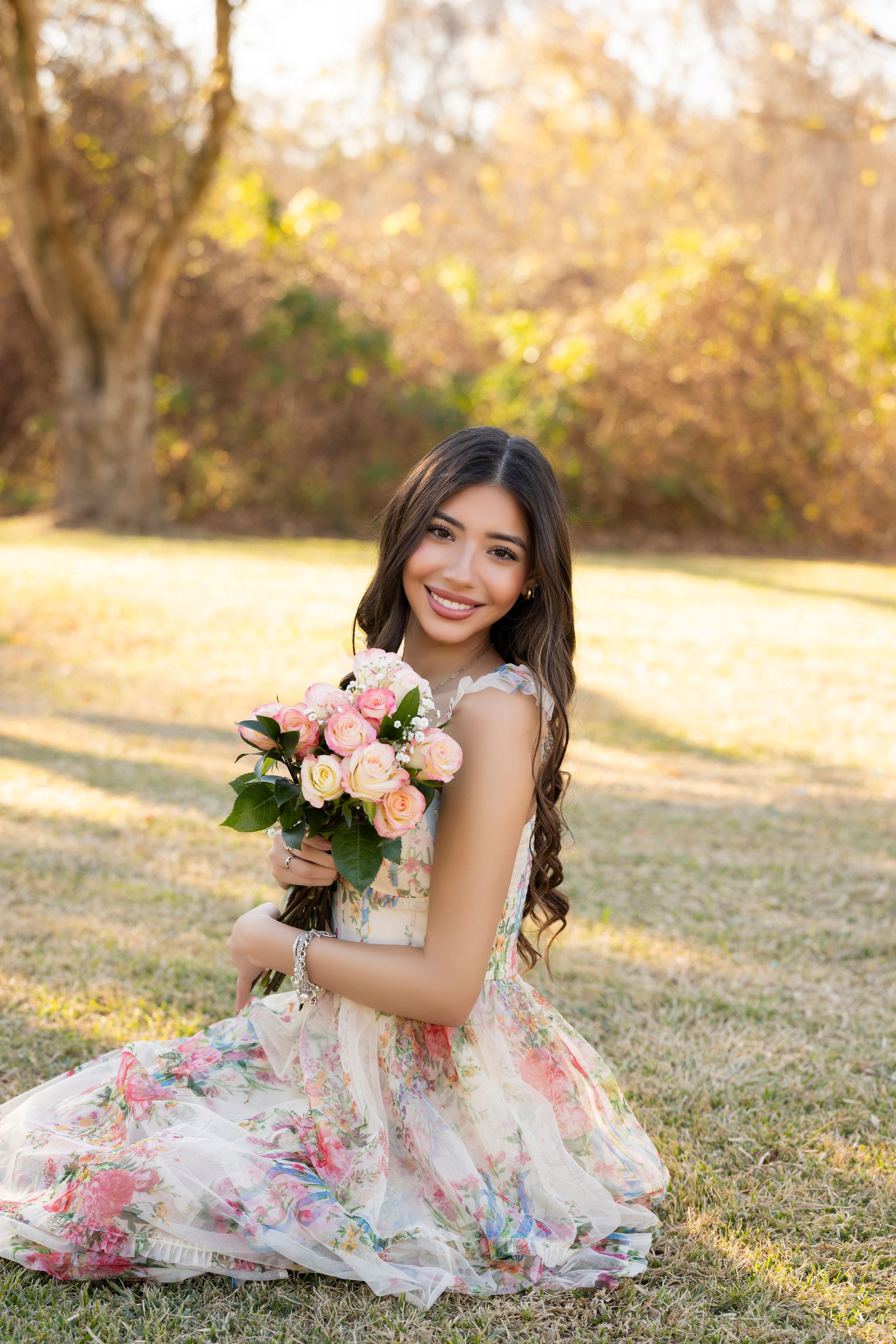 Outdoor portrait session in floral dress with pink roses during golden hour.
