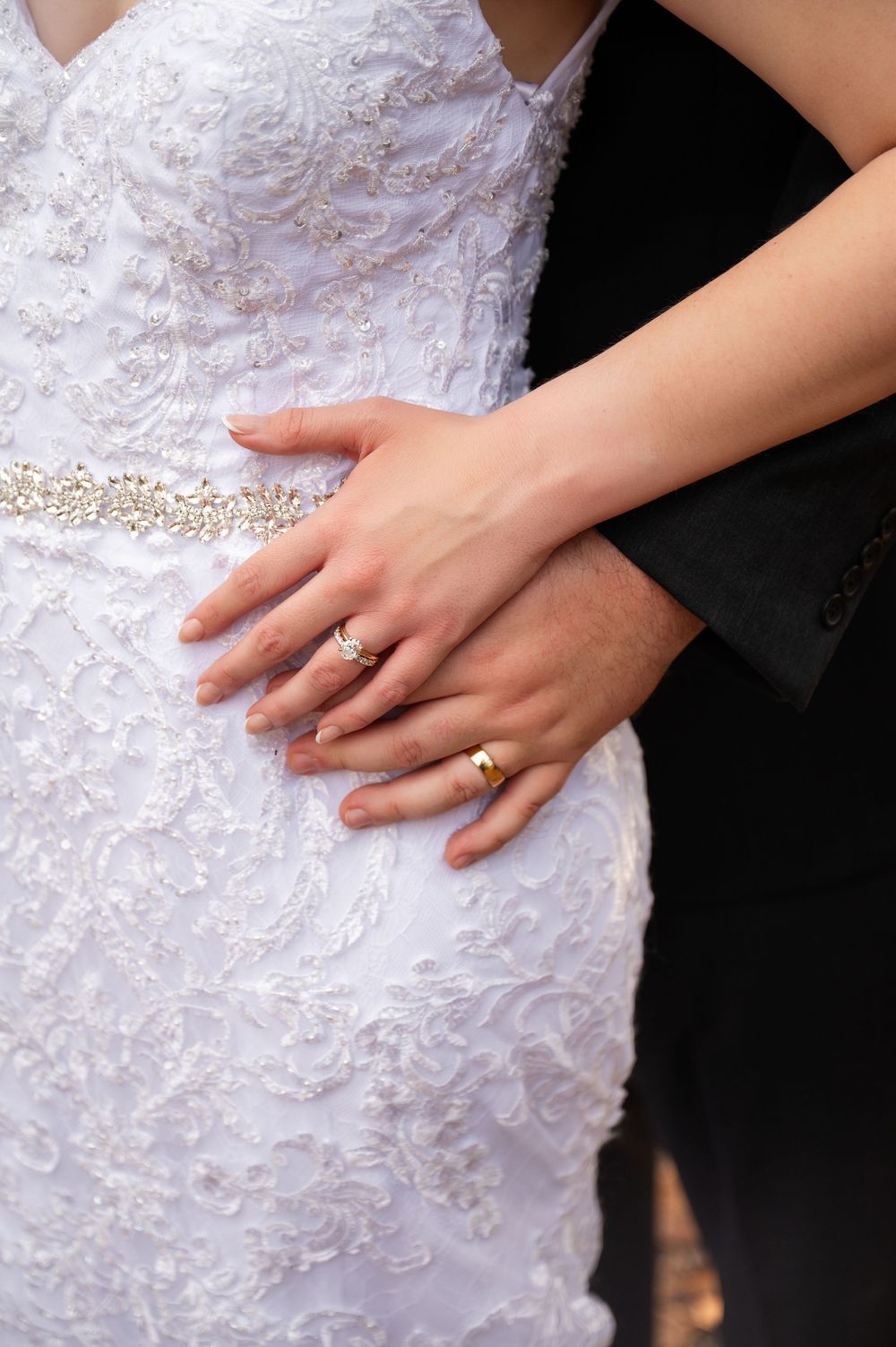 Close-up of an elegant wedding ring and lace dress details.