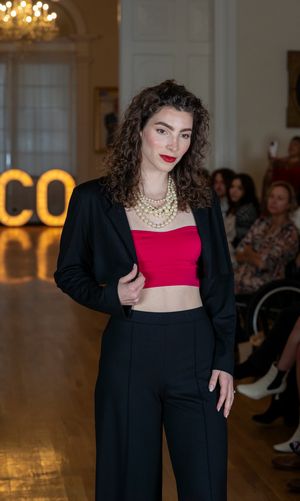 Model presents black blazer and red crop top ensemble during fashion show.