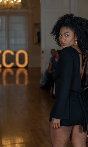 Model walks runway in fitted black ensemble against backdrop with glowing ECO signage.