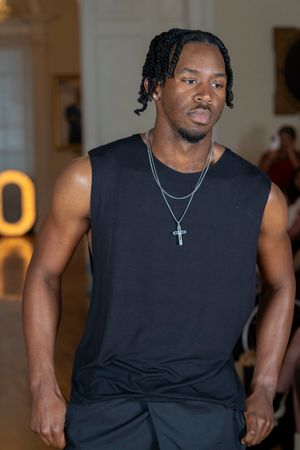 Athletic person in black sleeveless shirt with cross necklace shown in multiple poses against light background.