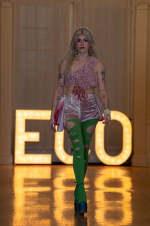 Models showcase pink and green ensembles on a runway with illuminated ECO letters in the background.