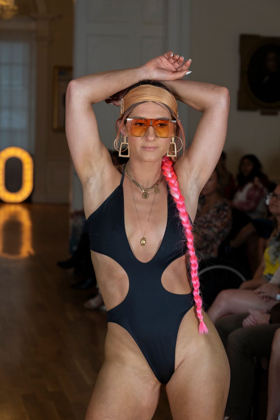 A person in a black leotard performs a contemporary dance movement sequence in a studio space.