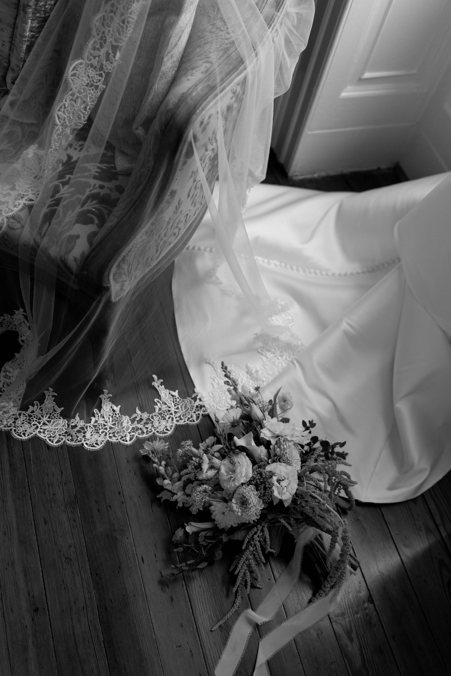 Elegant bride in strapless lace wedding gown descending wooden staircase in soft natural light.