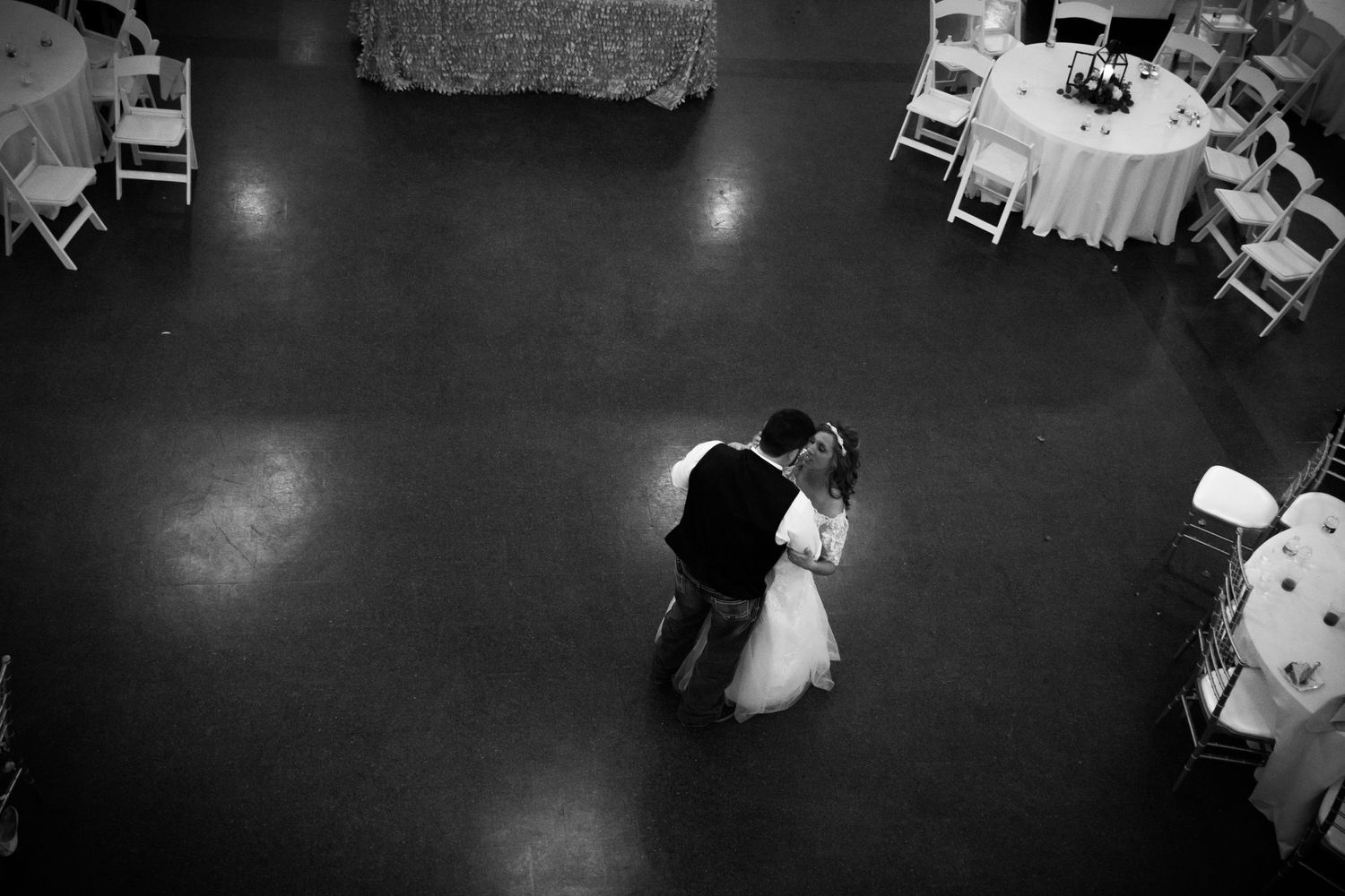 Black and white photograph of a couple dancing at their wedding reception in an elegantly decorated ballroom.