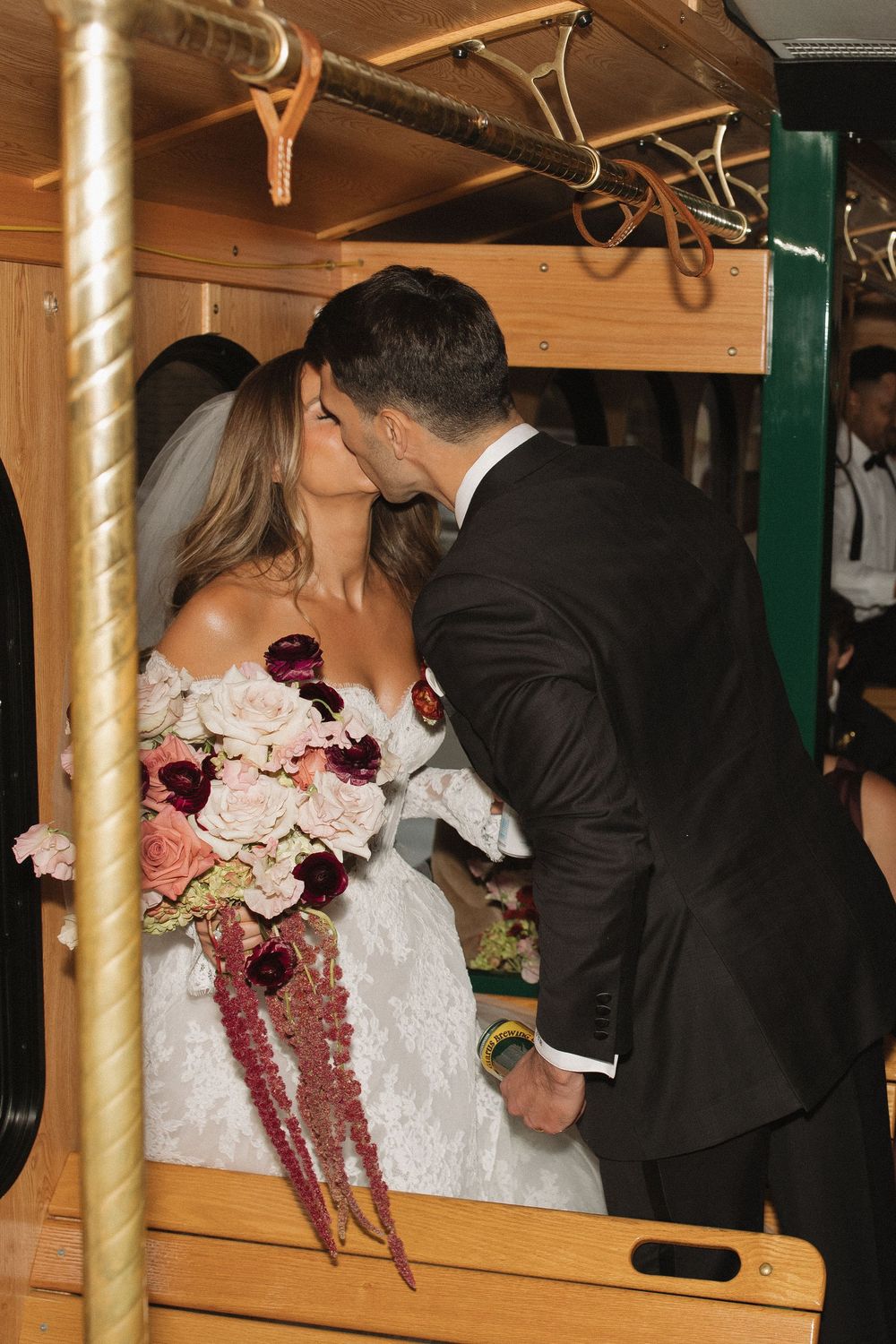 A couple shares a romantic moment on a carousel during their wedding, with pink and burgundy florals visible.