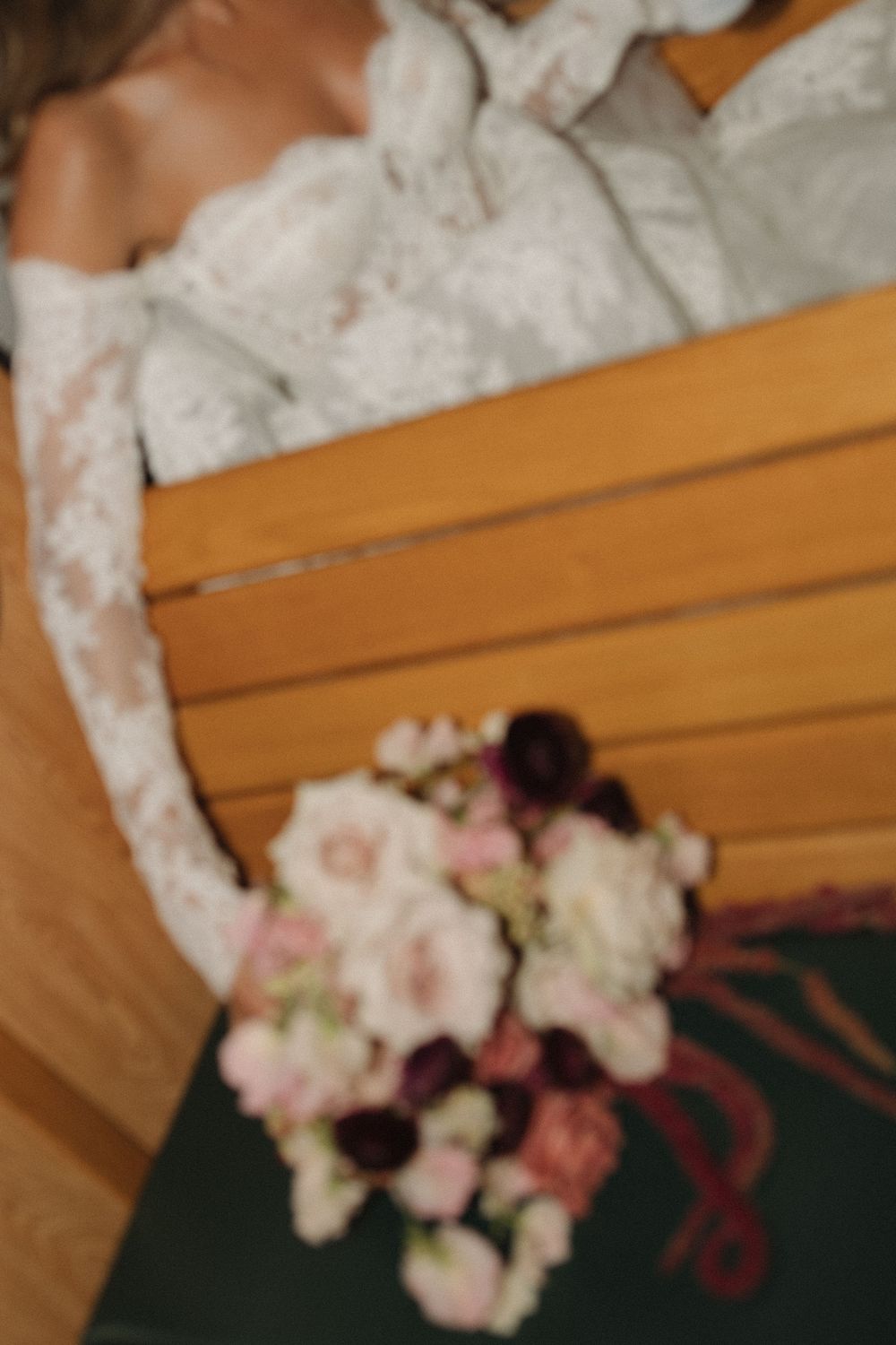 A delicate bouquet of pink and white flowers with lace details rests on a wooden surface.