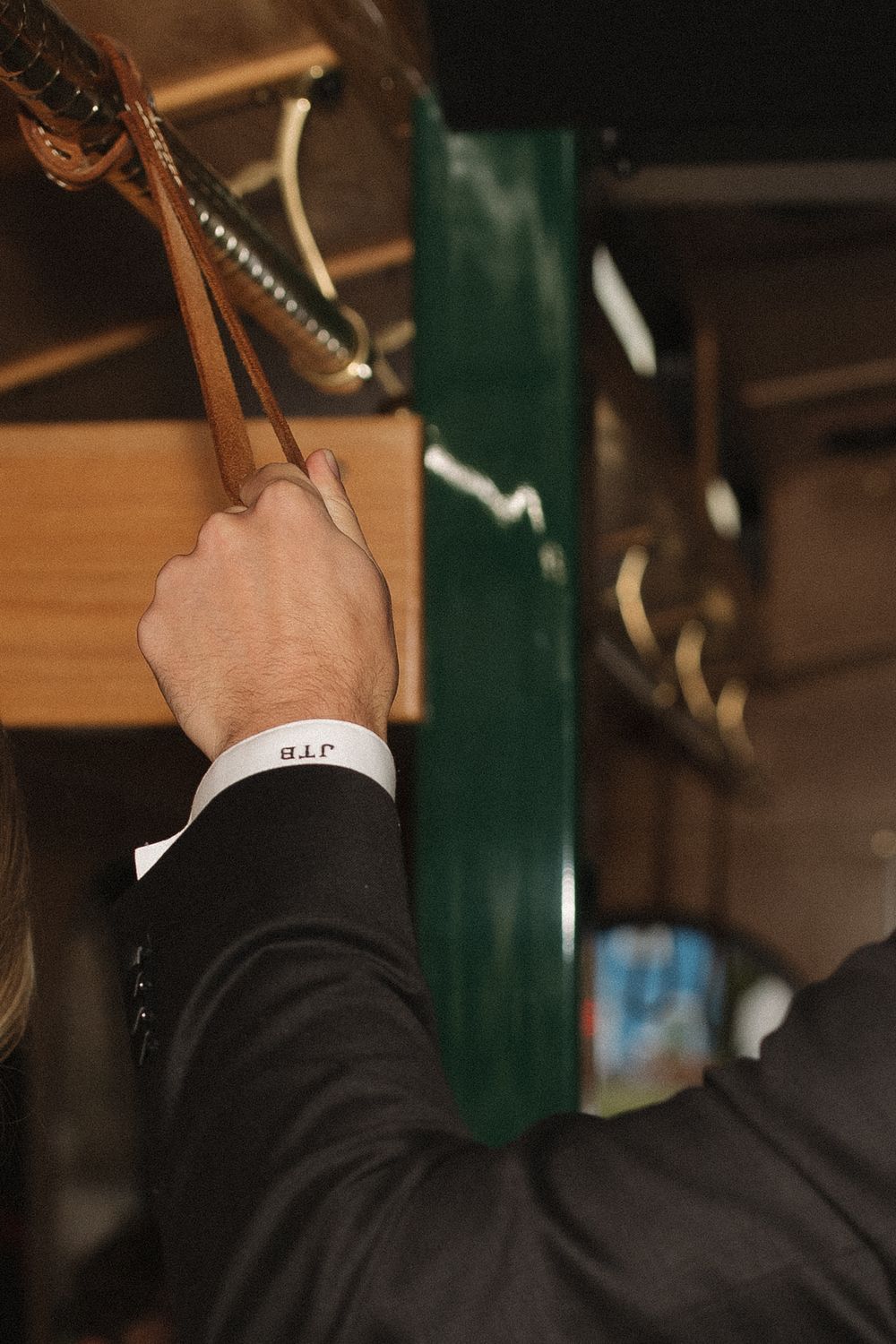 A close-up view of hands holding onto golden carousel poles in dim lighting.