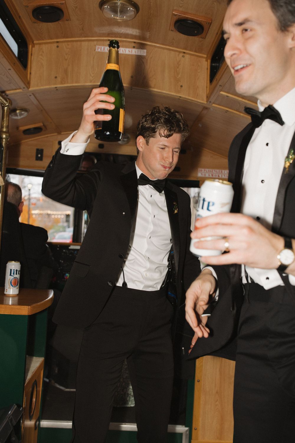 Men in formal tuxedos enjoying drinks and conversation at what appears to be a social gathering or celebration.