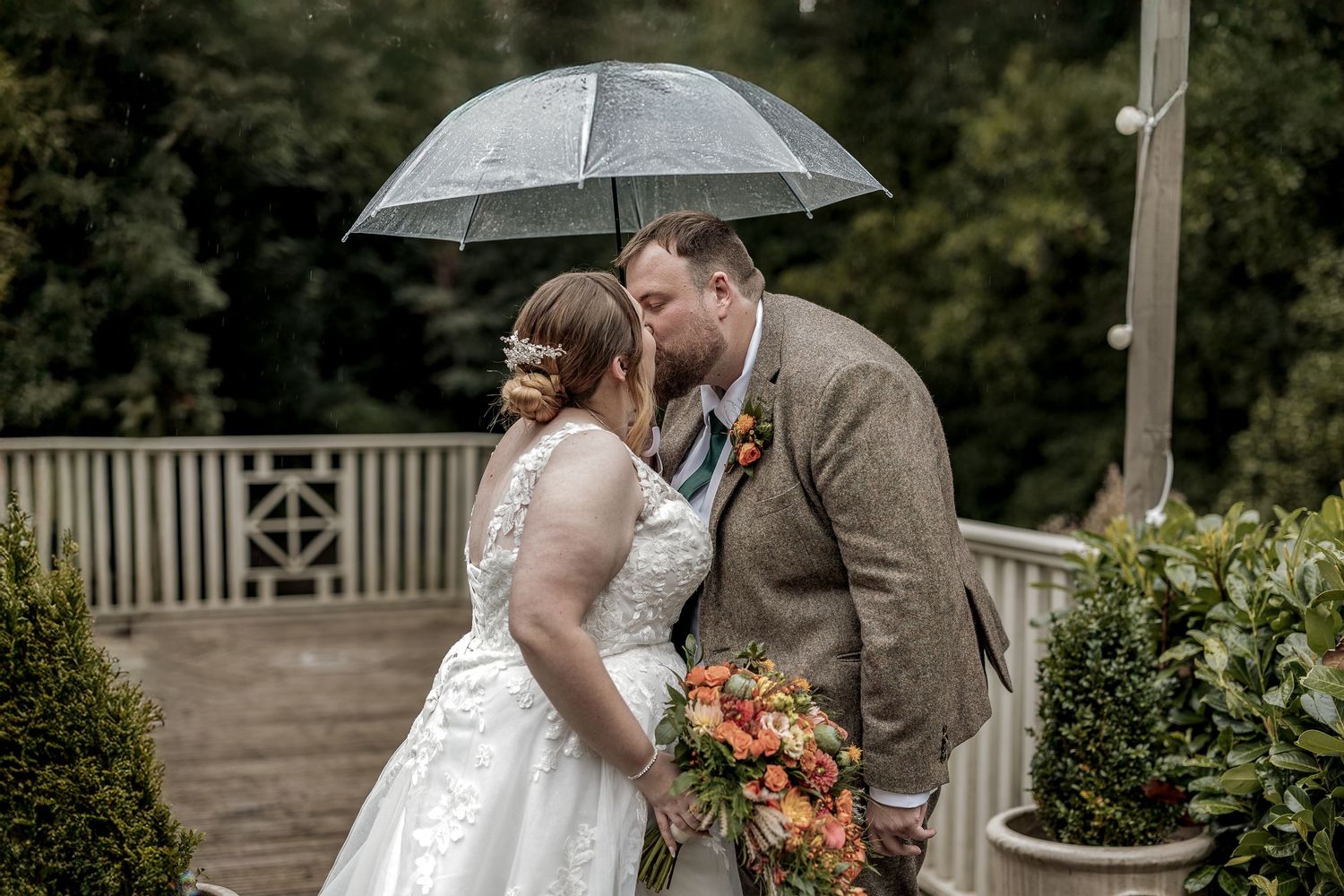 A unobtrusive wedding portrait on a rainy day with an umbrella.