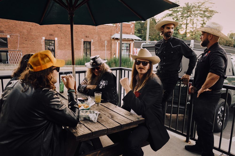 Friends gathered at an outdoor patio table sharing drinks and conversation.