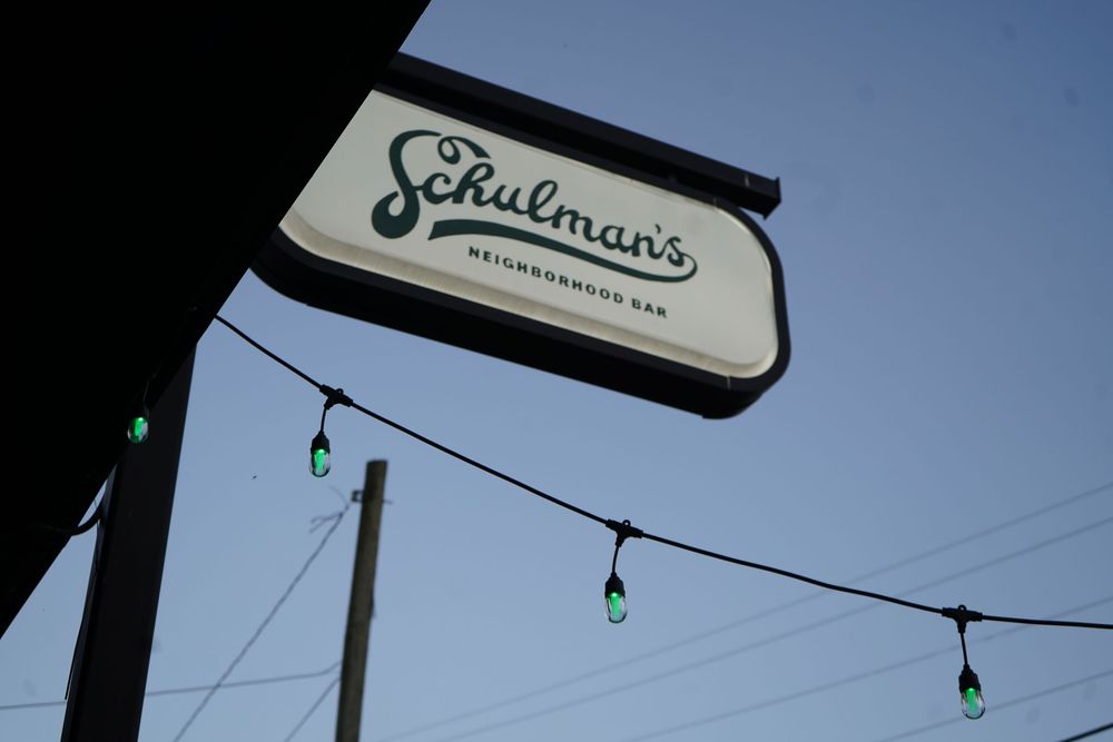 Vintage-style business sign silhouetted against a bright blue sky.