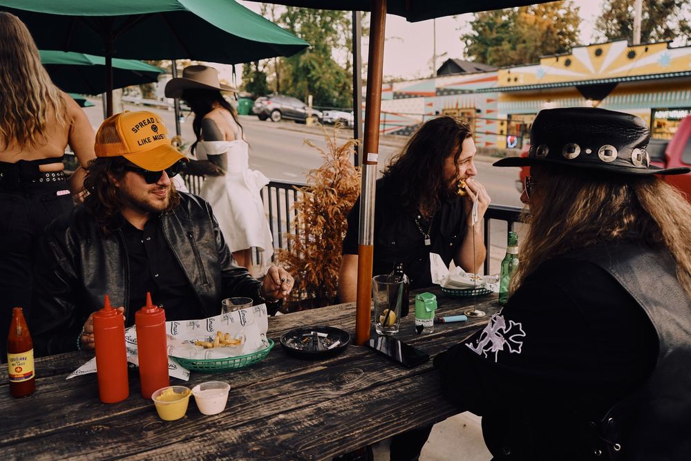 People socializing at an outdoor bar patio with string lights overhead.