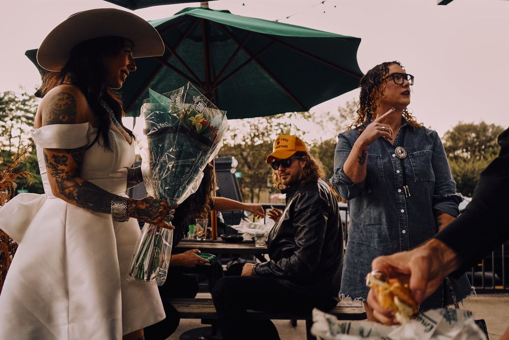 People enjoying food and drinks under green umbrellas at an outdoor venue.