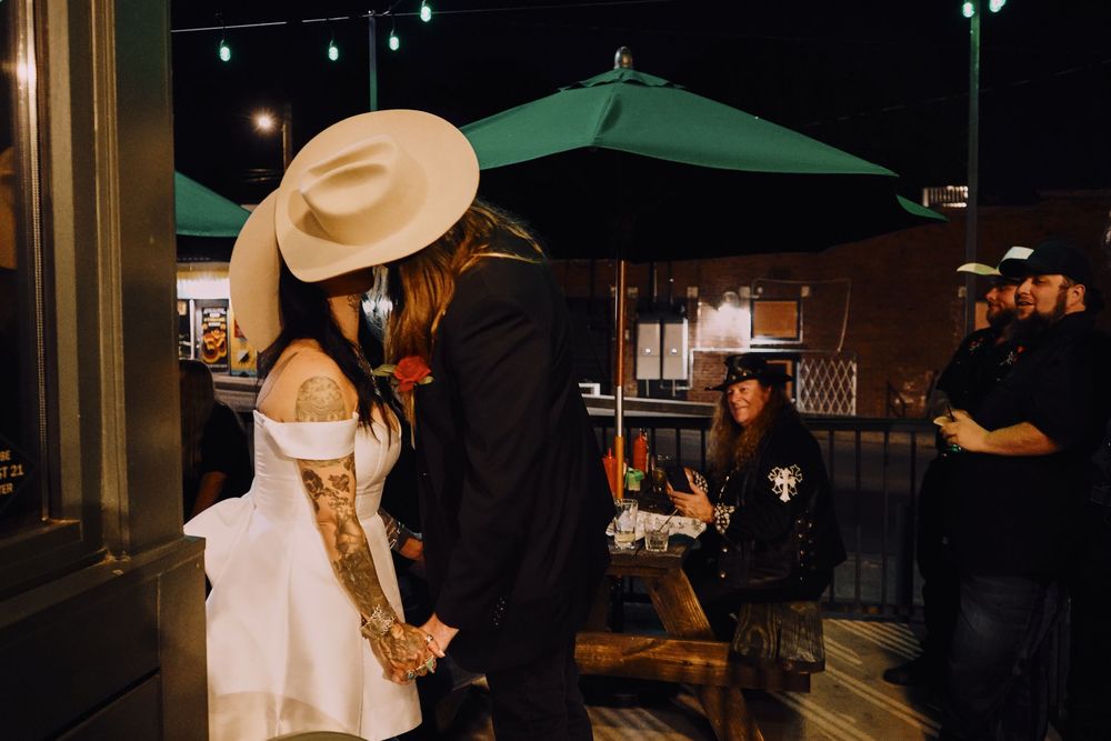 Outdoor evening celebration with western-themed attire under green umbrellas.