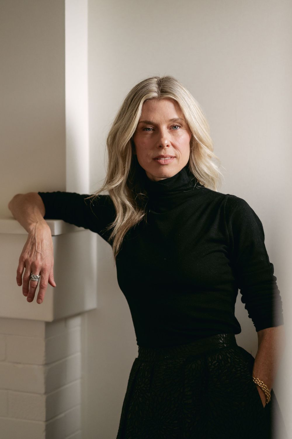 A person in a black turtleneck sweater poses against a neutral wall in a series of cropped portrait shots.