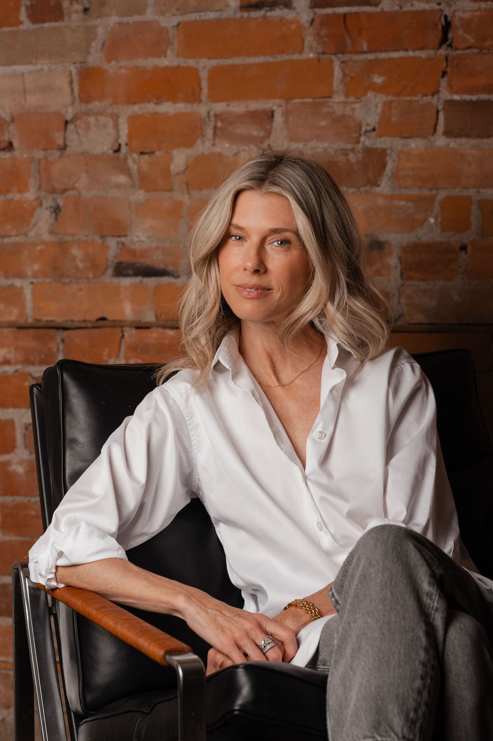 Professional portrait series against brick wall showing relaxed poses in white shirt and gray pants.