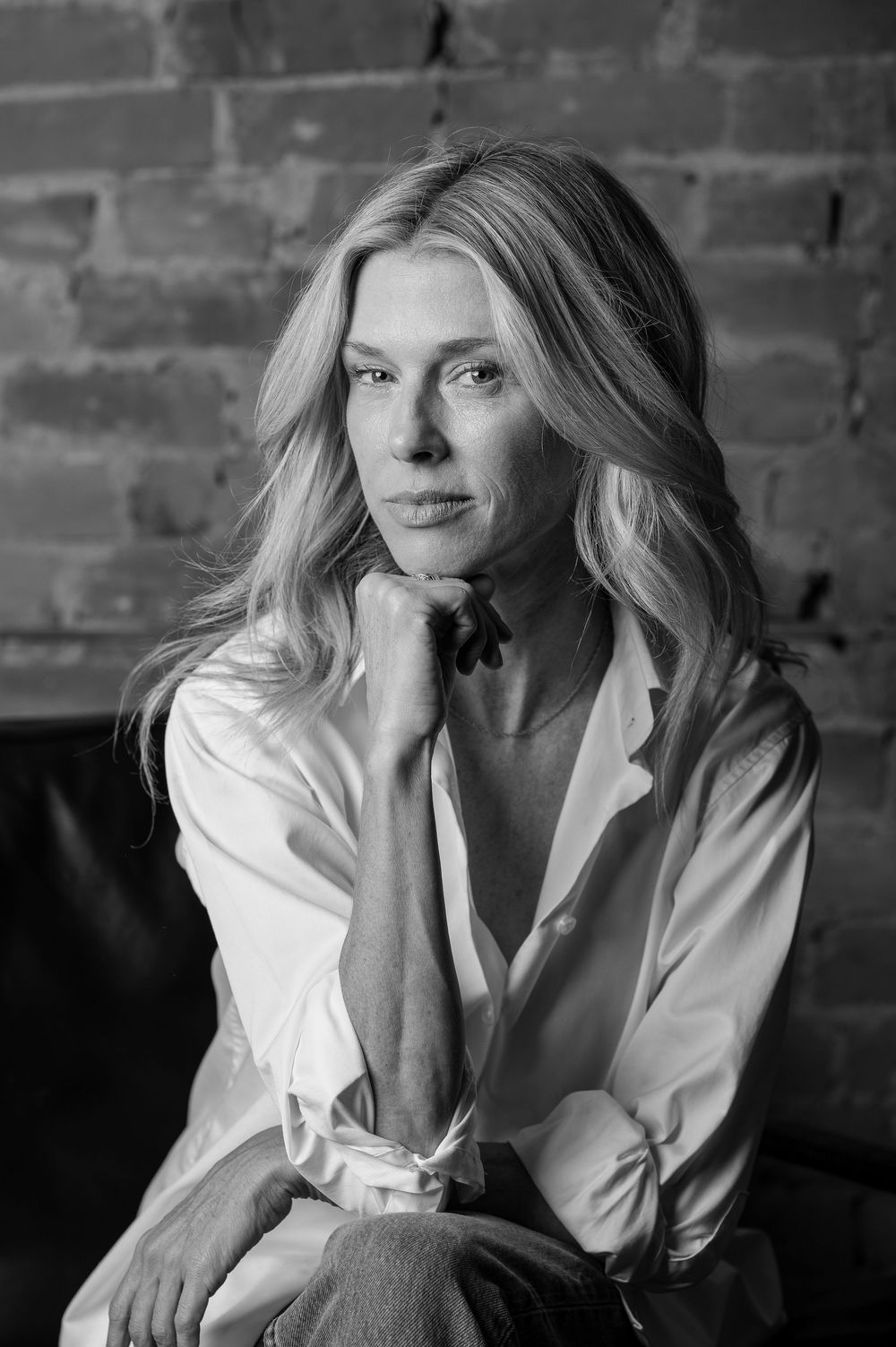A black and white portrait series showing someone in a white button-down shirt against a brick wall background.