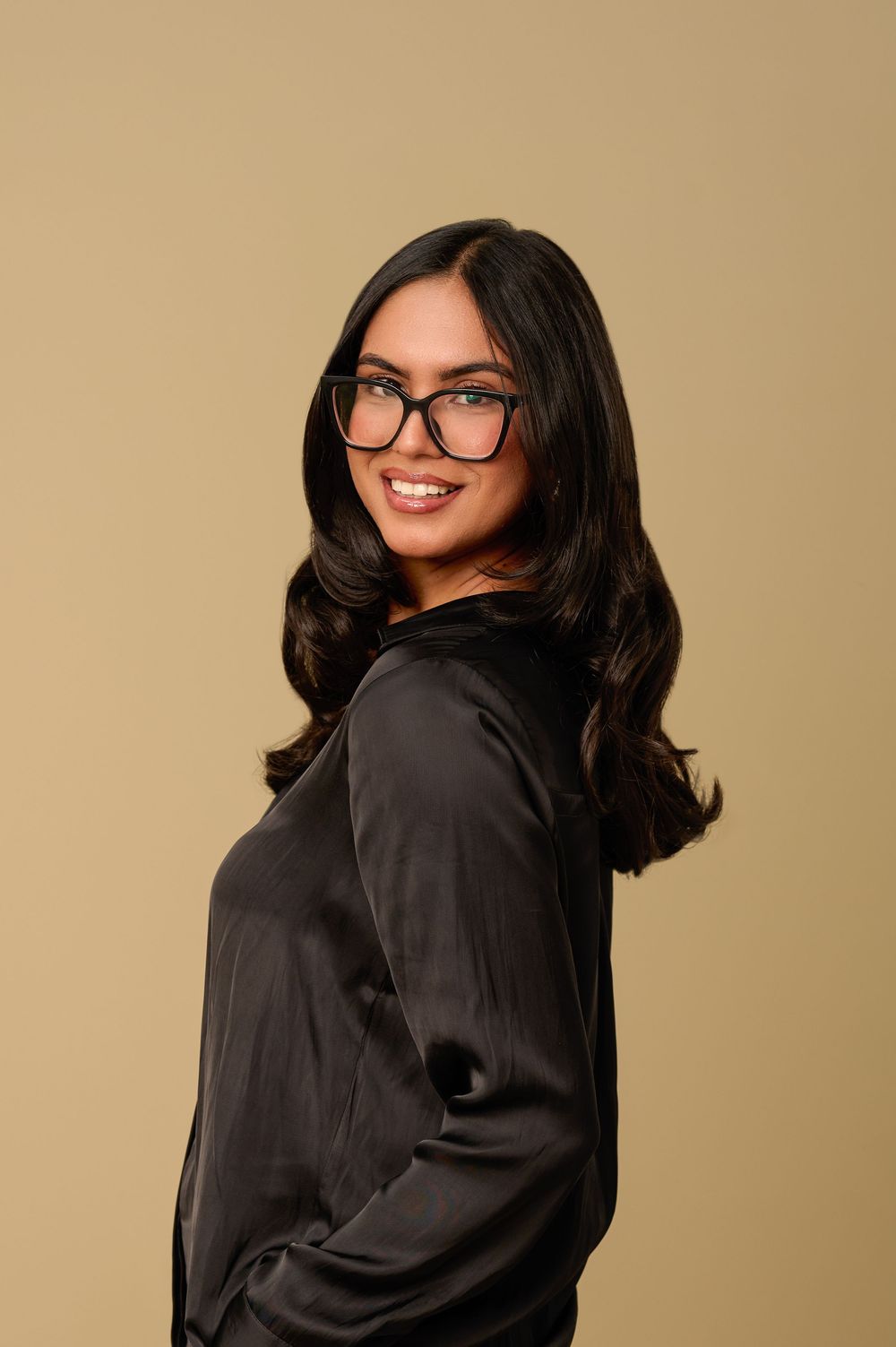 A series of four photos showing someone in a black shirt posing against a beige background with glasses and dark hair.