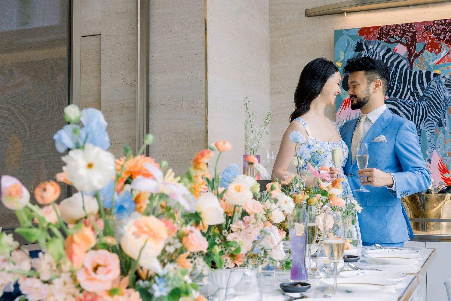 Wedding reception table decorated with elegant peach and coral floral centerpieces in a bright venue with city views.