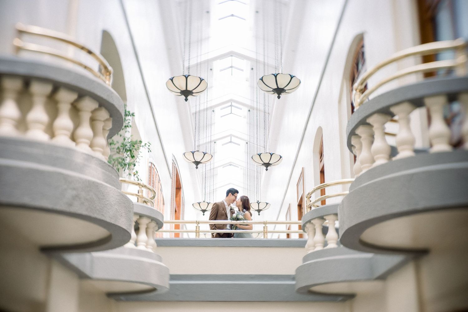 Elegant white marble staircase with ornate railings and chandeliers in a luxurious wedding venue interior.
