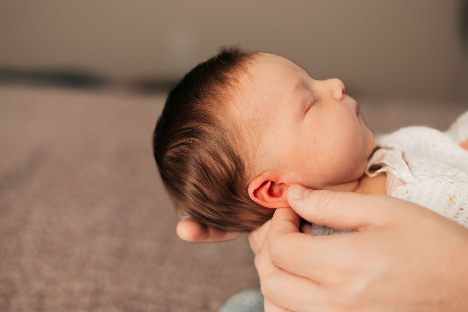Close-up of newborn baby with dark hair being gently cradled in loving hands |Newborn Photos When You Don't Feel Like Yourself