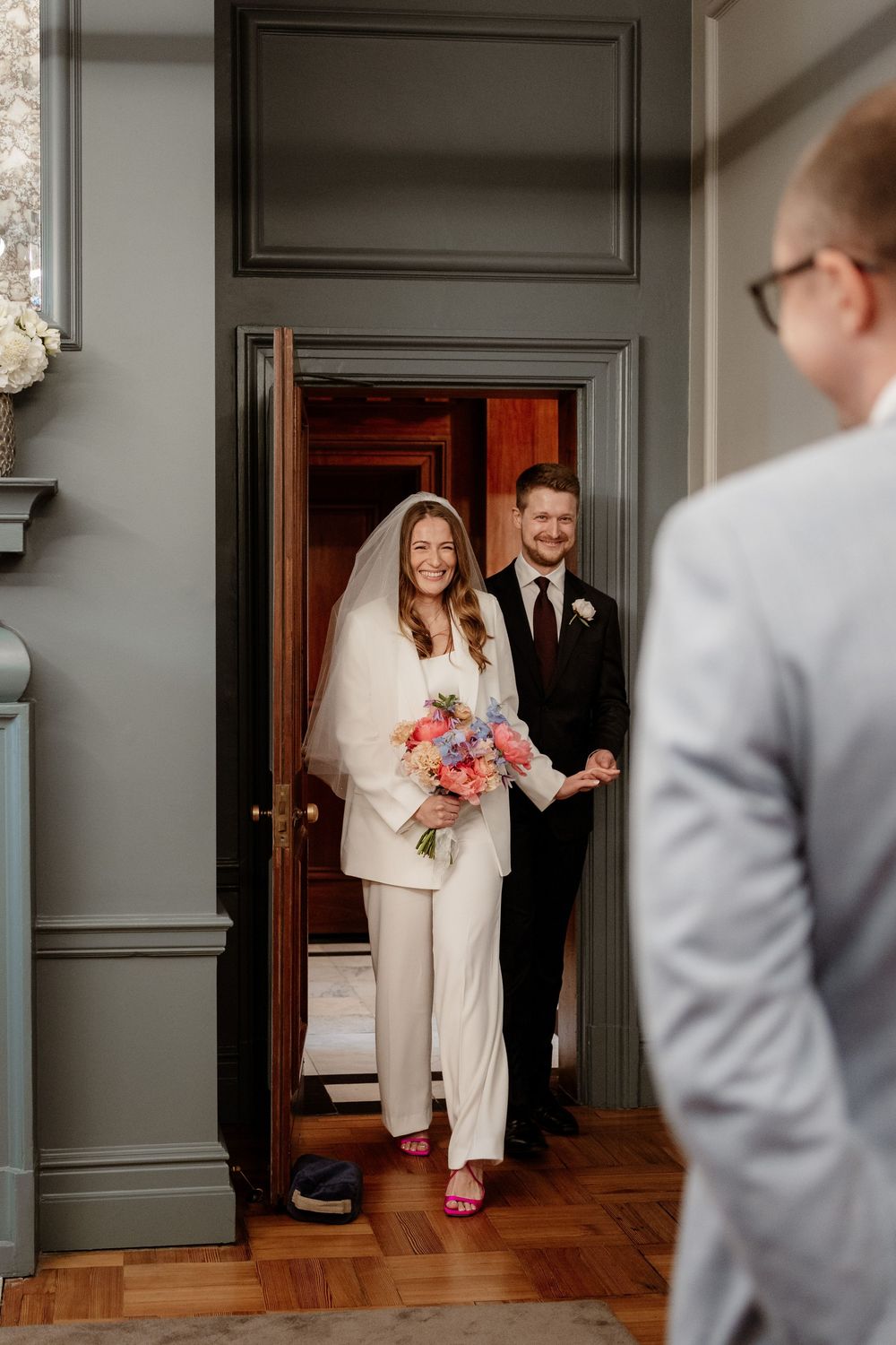 A couple enters through a doorway in formal attire during a wedding ceremony at an elegant venue.