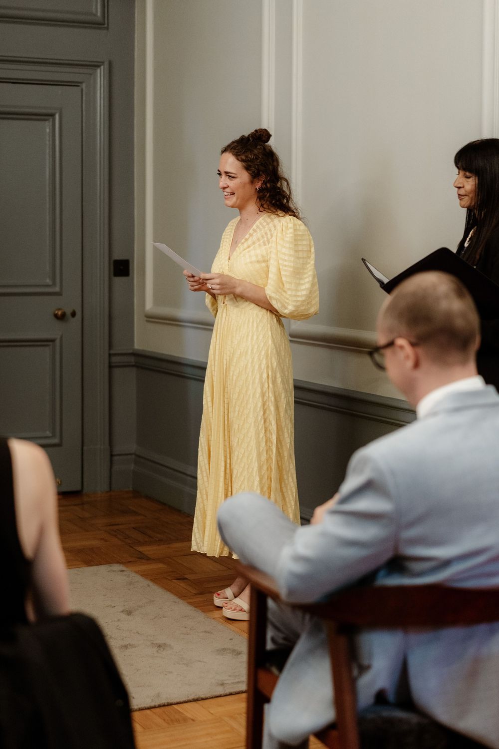 A series of photos showing a person in a yellow dress posing while being photographed in an elegant room with hardwood floors.