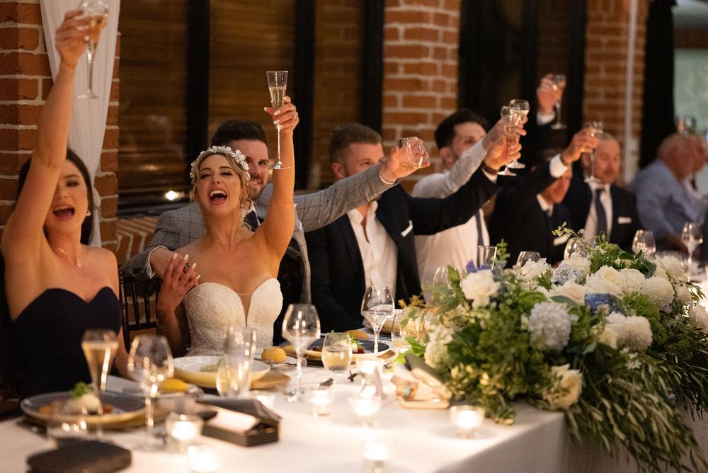 Wedding party raises champagne glasses in joyful toast at elegantly decorated reception.