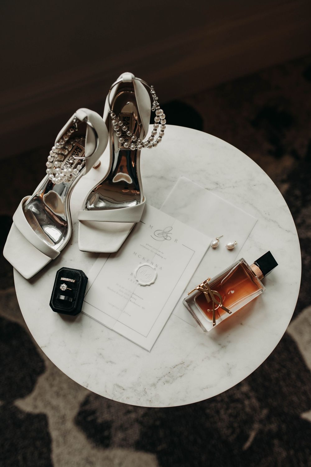 Elegant bridal flat lays featuring pearl-adorned heels, perfume, wedding invitation, and jewelry on marble.