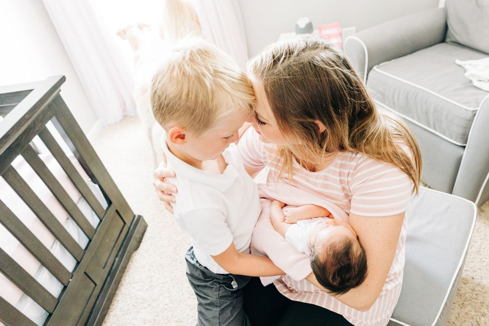 A tender moment between a mother, her son, and newborn baby shown against white backgrounds in Charlotte, NC.