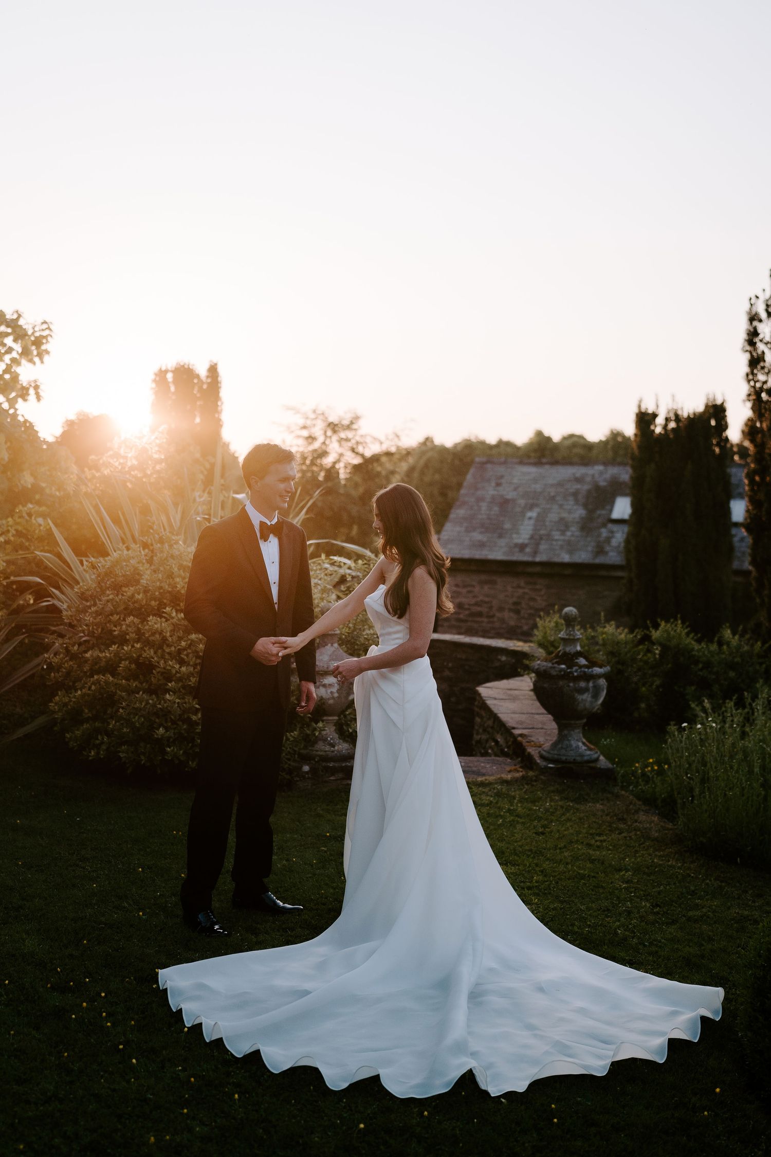 groom holding brides hand during an intimate moment in the setting sun at dewsall court in herefordshire