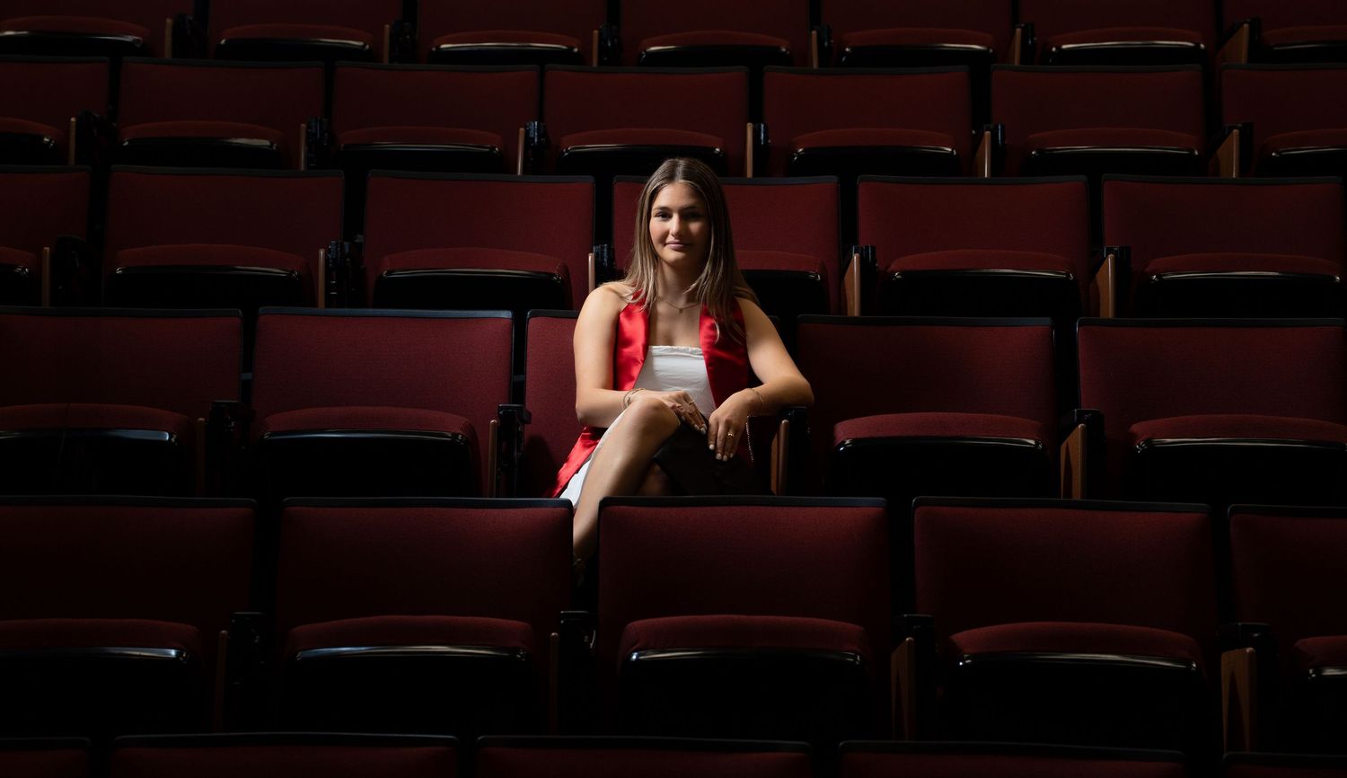 Empty red theater seats arranged in rows inside a dark auditorium.