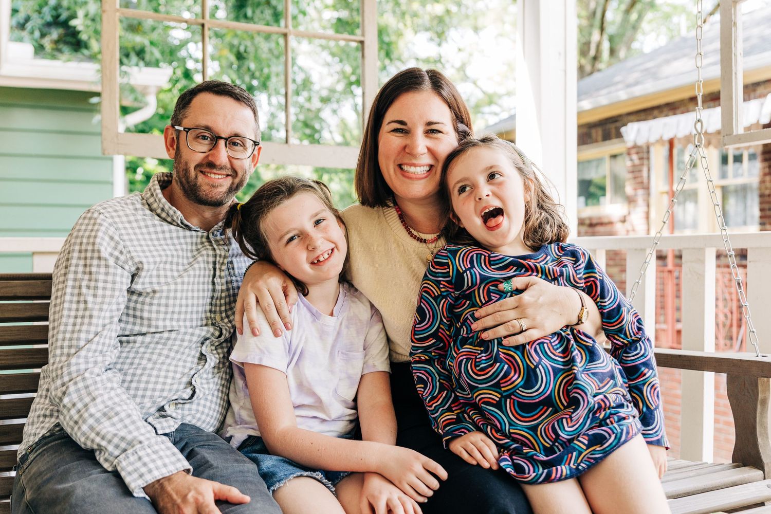 A family shares joyful moments together while sitting on a porch of a mint green house in Charlotte, NC.