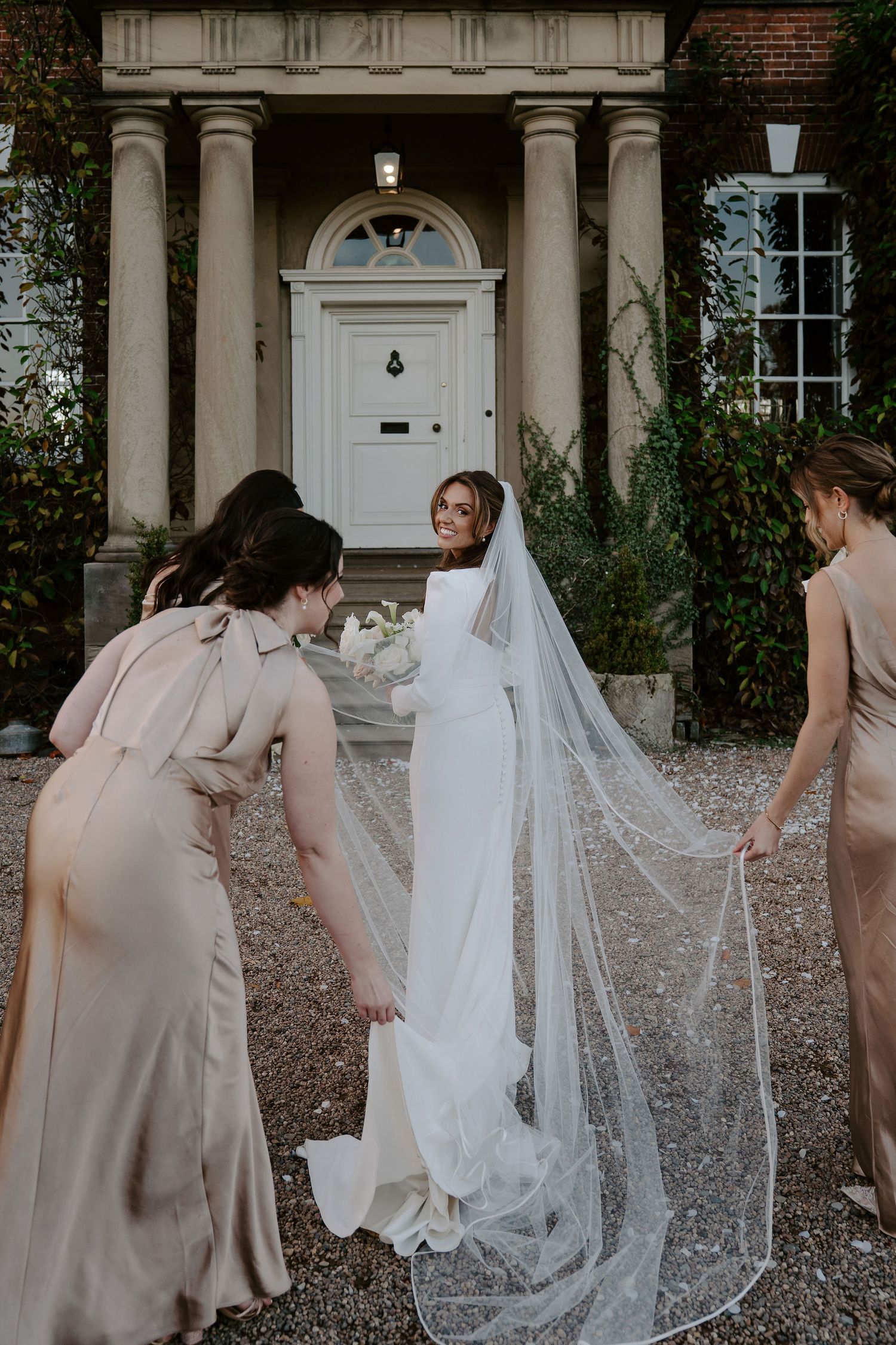 bridesmaids helping with brides dress outside Iscoyd park