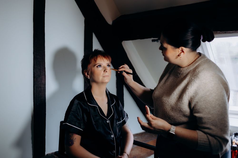 A makeup artist applies cosmetics to a model in a professional studio setting.